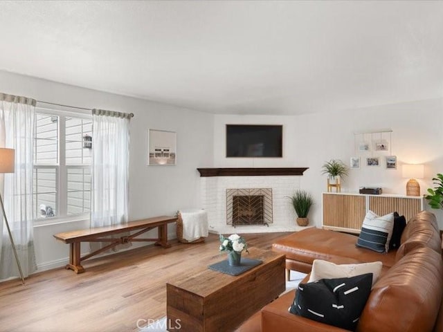 living room featuring a brick fireplace and wood finished floors