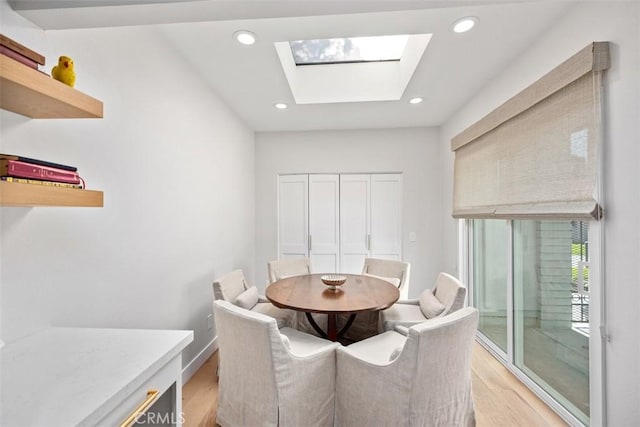 dining space with recessed lighting, a skylight, and light wood finished floors