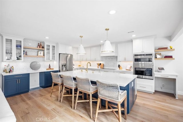 kitchen featuring a breakfast bar area, blue cabinetry, appliances with stainless steel finishes, open shelves, and custom range hood