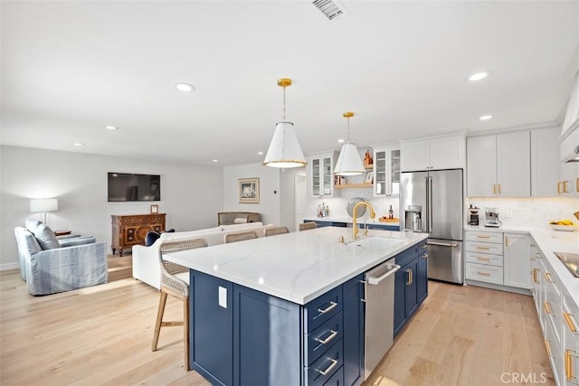 kitchen featuring stainless steel appliances, open floor plan, visible vents, and a sink