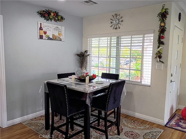 dining area with baseboards, visible vents, a healthy amount of sunlight, and wood finished floors