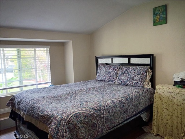 bedroom with wood finished floors, baseboards, and lofted ceiling
