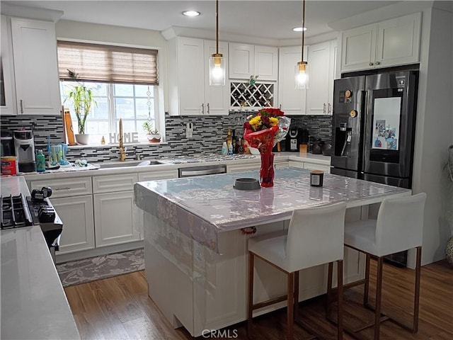 kitchen featuring decorative backsplash, a kitchen island, a kitchen bar, white cabinets, and black fridge
