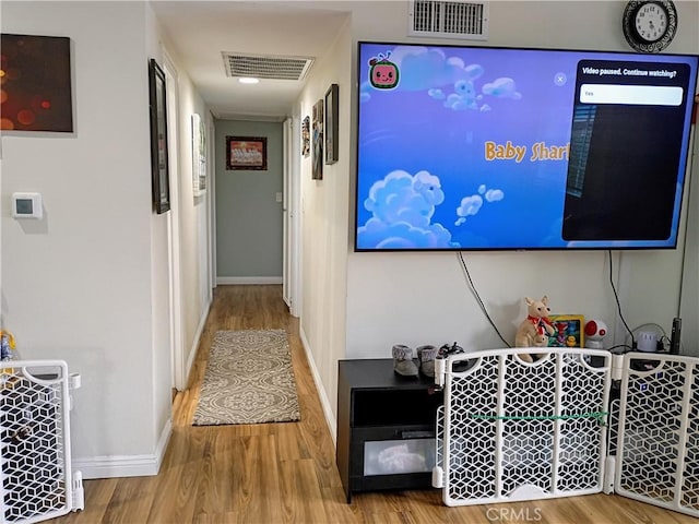 hallway featuring baseboards, visible vents, and wood finished floors