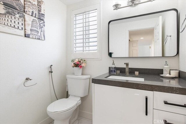 bathroom with baseboards, vanity, toilet, and marble finish floor