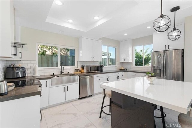 kitchen with appliances with stainless steel finishes, a sink, a kitchen breakfast bar, marble finish floor, and recessed lighting