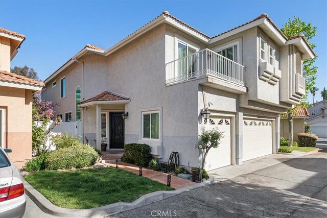 view of front of home with a garage, stucco siding, and a balcony