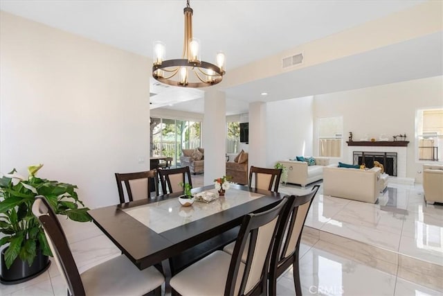 dining space featuring visible vents, marble finish floor, a notable chandelier, and a fireplace