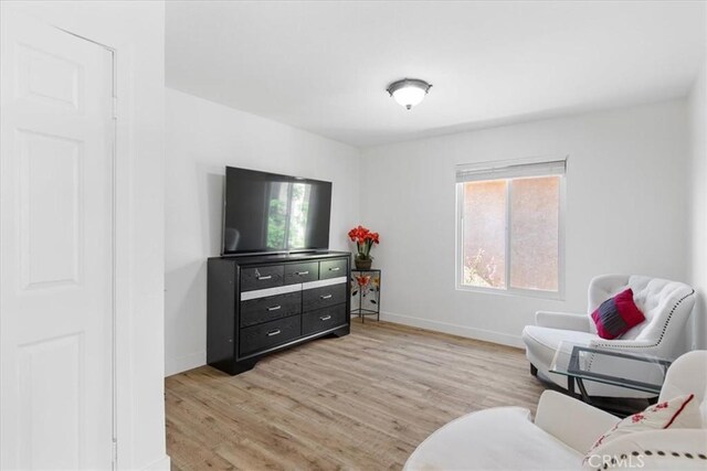 sitting room featuring a healthy amount of sunlight, baseboards, and light wood-type flooring