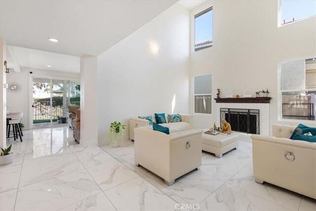 living room featuring recessed lighting, a fireplace, marble finish floor, and a wealth of natural light