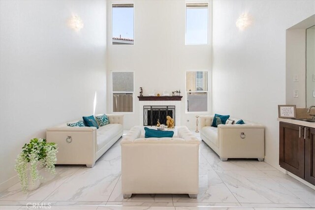 living area featuring marble finish floor, a high ceiling, and a fireplace
