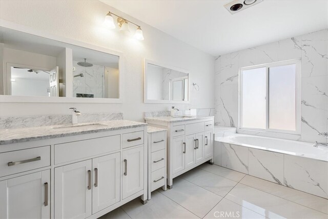 bathroom with a sink, a marble finish shower, marble finish floor, two vanities, and a garden tub