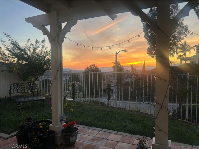 patio terrace at dusk featuring fence