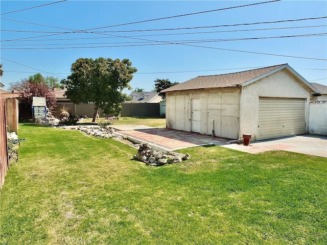 view of yard with fence, an outdoor structure, and concrete driveway