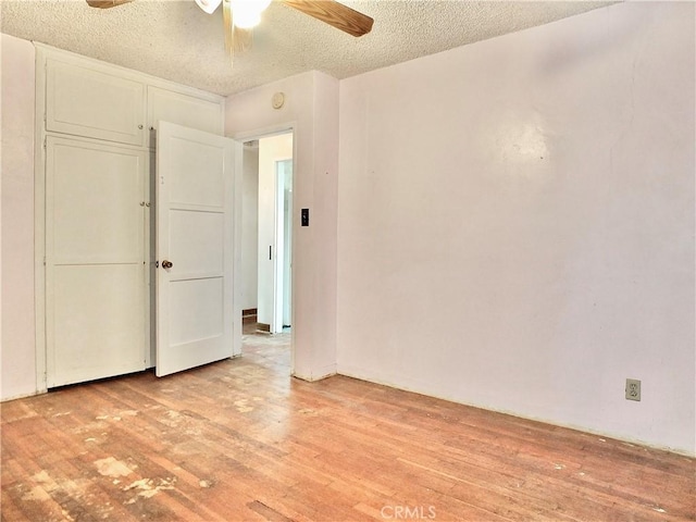 unfurnished bedroom featuring a closet, a textured ceiling, light wood finished floors, and a ceiling fan