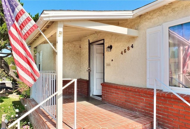 view of exterior entry featuring covered porch and stucco siding