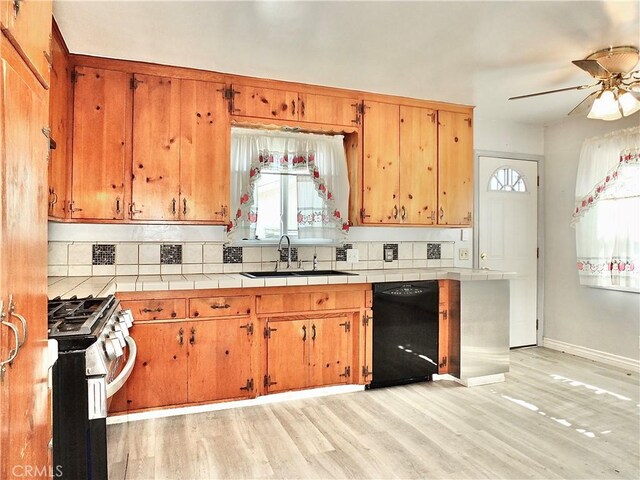 kitchen featuring stainless steel gas range, a sink, dishwasher, tile counters, and tasteful backsplash