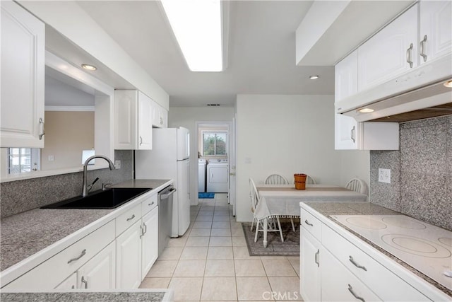 28970 Exmoor Ct, Menifee, CA 92586 - kitchen featuring washing machine and dryer, under cabinet range hood, a sink, white electric cooktop, and light tile patterned floors