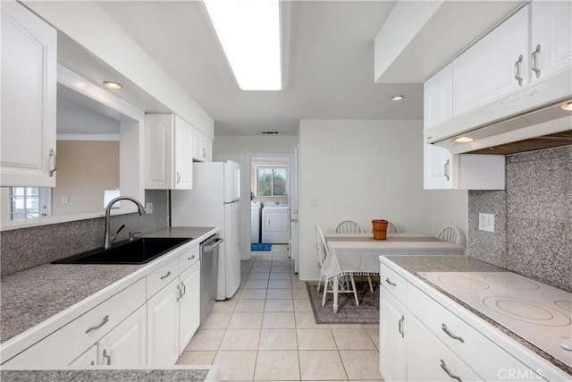 28970 Exmoor Ct, Menifee, CA 92586 - kitchen featuring white electric cooktop, under cabinet range hood, independent washer and dryer, and decorative backsplash