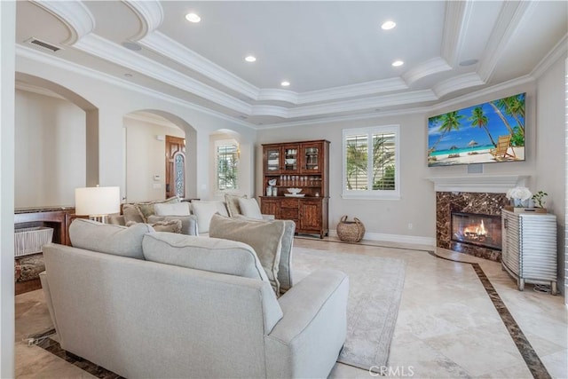 living room featuring arched walkways, visible vents, ornamental molding, and a raised ceiling