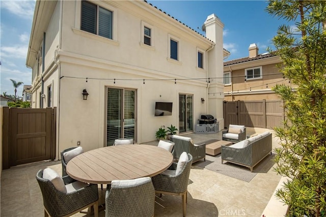 back of house with an outdoor living space, a chimney, a patio area, fence, and stucco siding
