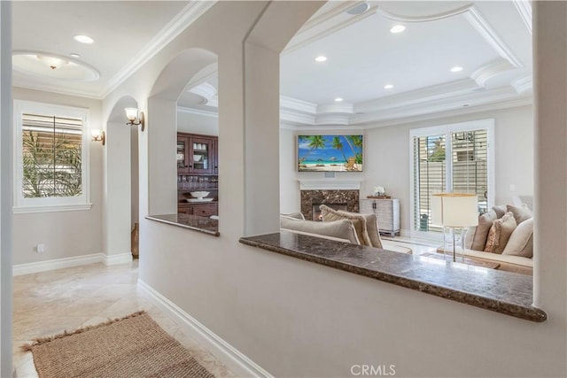 hall featuring crown molding, arched walkways, a tray ceiling, and recessed lighting