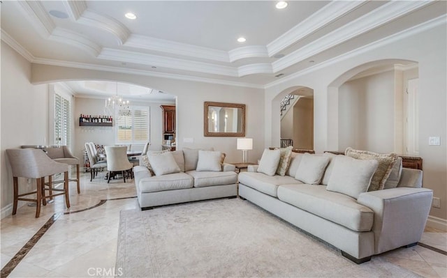 living room with ornamental molding, baseboards, a raised ceiling, a chandelier, and arched walkways