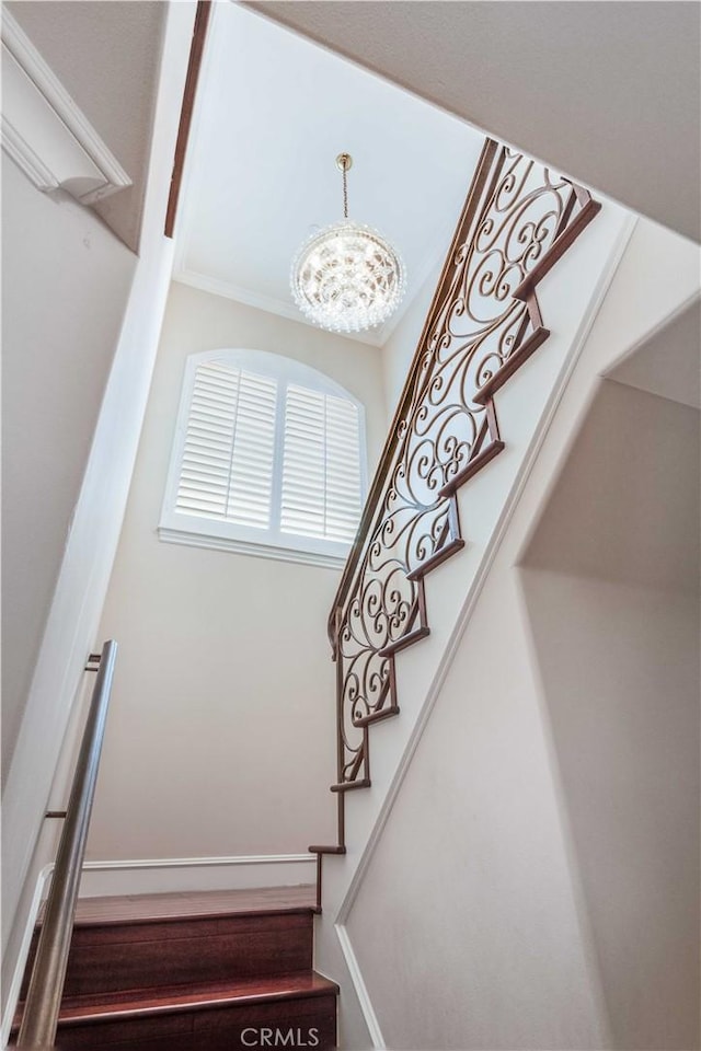stairs featuring crown molding and an inviting chandelier
