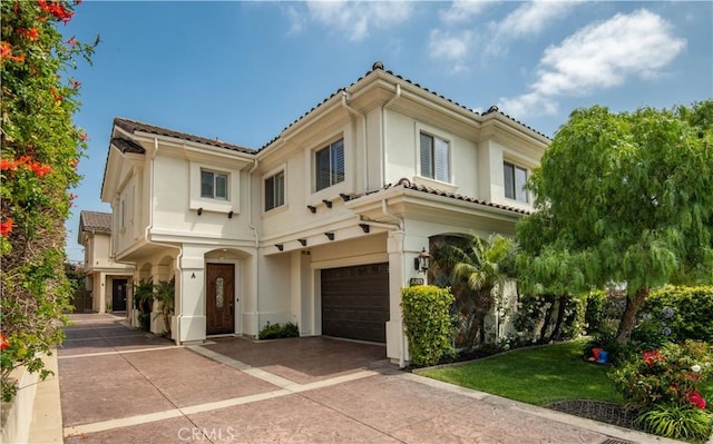 mediterranean / spanish-style home featuring a tiled roof, a garage, driveway, and stucco siding