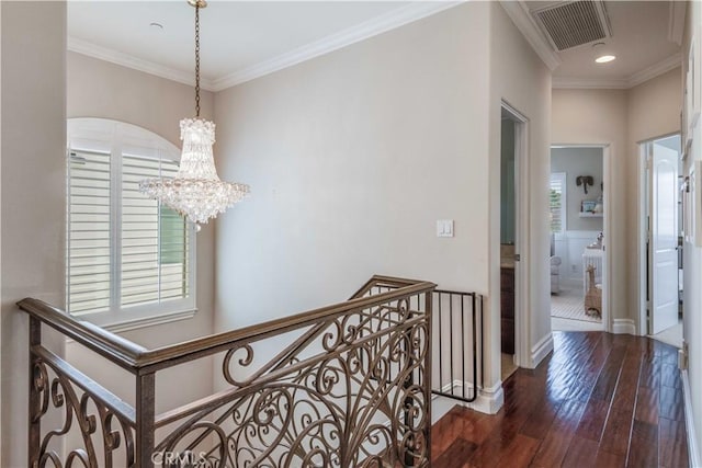 corridor featuring visible vents, ornamental molding, a healthy amount of sunlight, and hardwood / wood-style floors