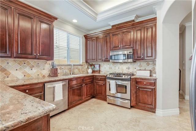 kitchen with a sink, arched walkways, ornamental molding, and stainless steel appliances