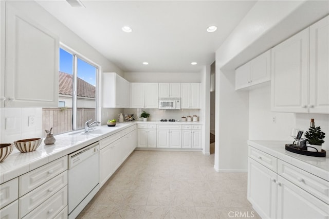 kitchen featuring a sink, white cabinets, and white appliances