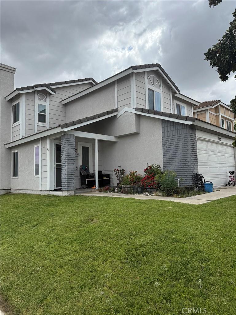 1822 W Westwind St, Colton, CA 92324 - traditional-style house with stucco siding, an attached garage, and a front lawn