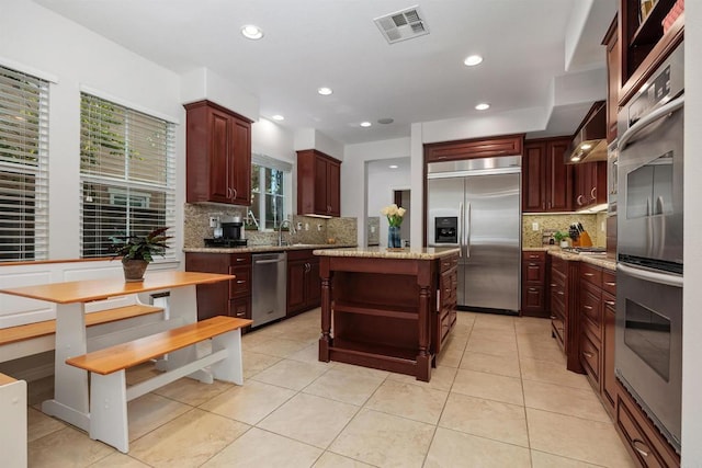kitchen featuring visible vents, open shelves, decorative backsplash, a center island, and appliances with stainless steel finishes