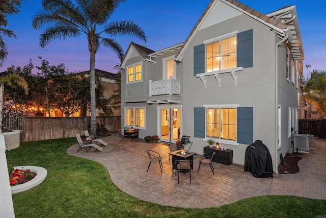 back of house with french doors, stucco siding, a lawn, and an outdoor fire pit