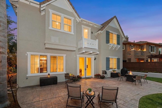 2258 Aventurine Pl, Carlsbad, CA 92009 - back of property at dusk with an outdoor fire pit, a balcony, stucco siding, and a patio area