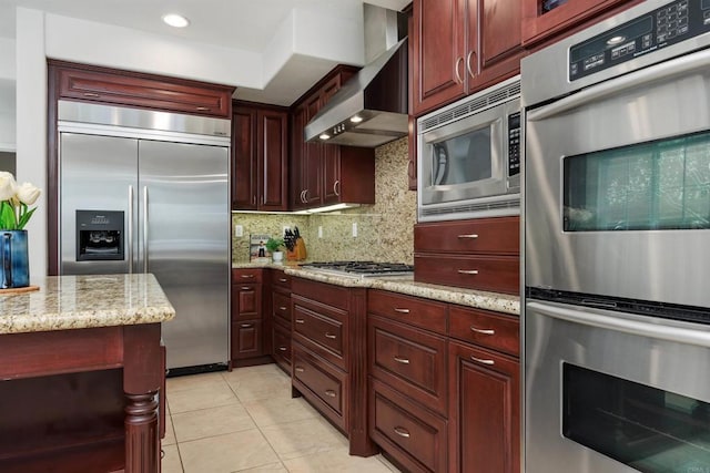 2258 Aventurine Pl, Carlsbad, CA 92009 - kitchen with built in appliances, wall chimney exhaust hood, reddish brown cabinets, tasteful backsplash, and light tile patterned floors