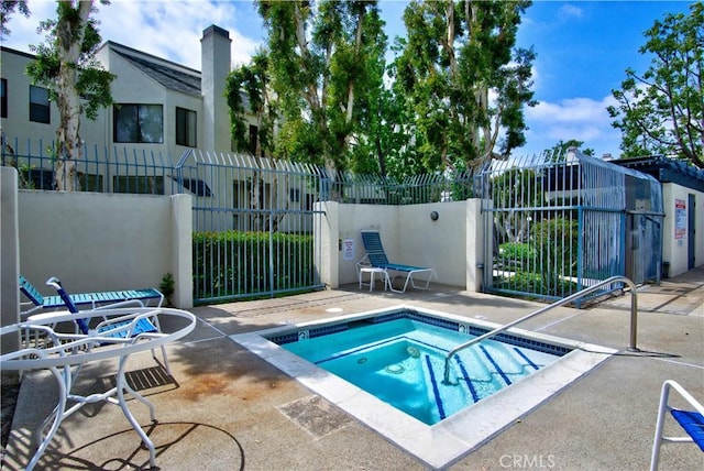 view of swimming pool with a patio, a hot tub, and fence