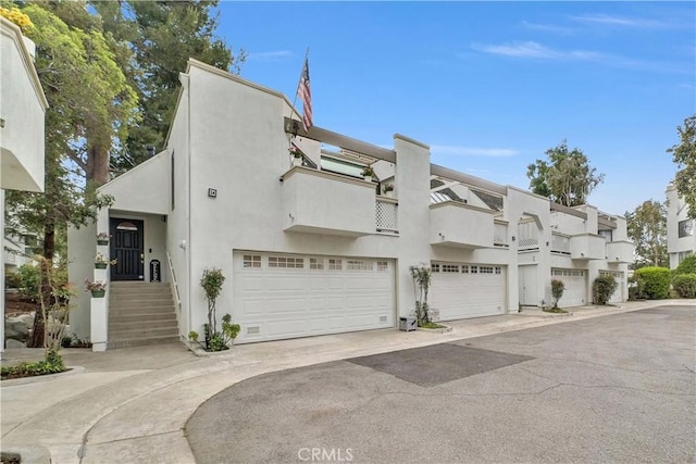 view of front of home with stucco siding, an attached garage, driveway, and a balcony