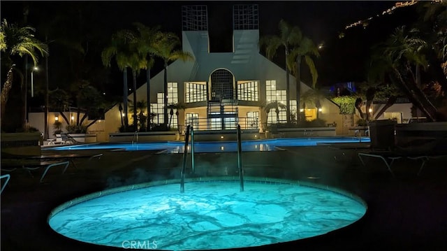 pool at twilight featuring a community pool and a community hot tub