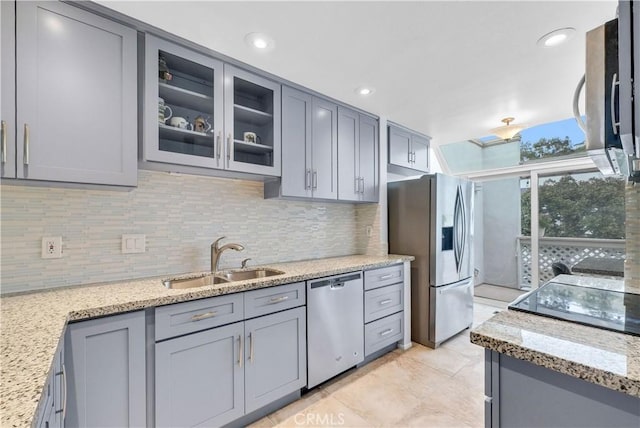 kitchen with a sink, gray cabinets, stainless steel appliances, and tasteful backsplash