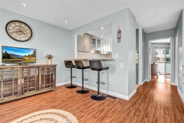 bar with light wood-style floors, baseboards, backsplash, and recessed lighting