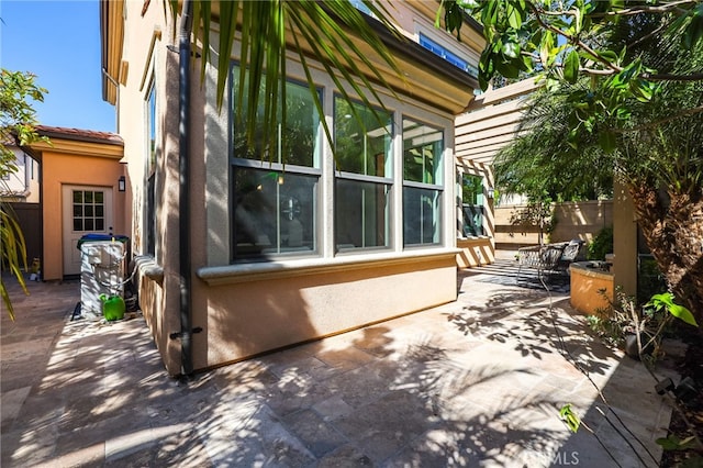 view of side of home featuring fence, a patio area, and stucco siding