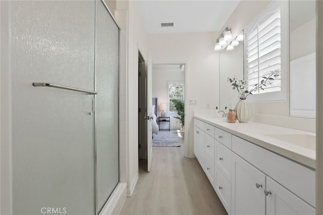 ensuite bathroom featuring visible vents, wood finished floors, ensuite bath, a sink, and a stall shower