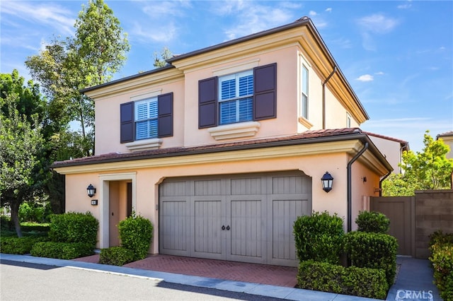 view of front of home featuring fence, stucco siding, an attached garage, and decorative driveway
