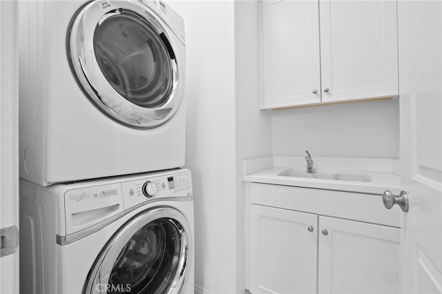 laundry room with a sink, stacked washer and dryer, and cabinet space