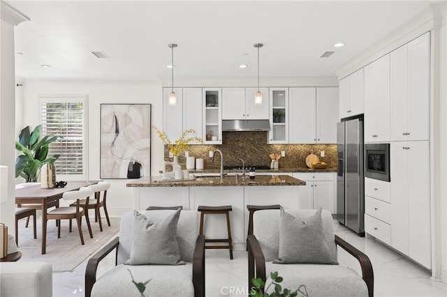 kitchen featuring appliances with stainless steel finishes, a sink, dark stone countertops, backsplash, and glass insert cabinets