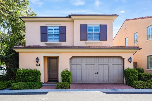 view of front of property with stucco siding, decorative driveway, and a garage