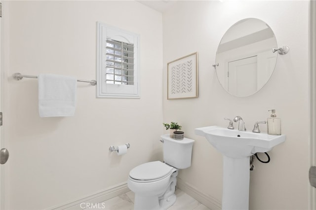 bathroom with toilet, baseboards, a sink, and marble finish floor