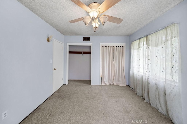 unfurnished bedroom with ceiling fan, light colored carpet, a textured ceiling, and visible vents